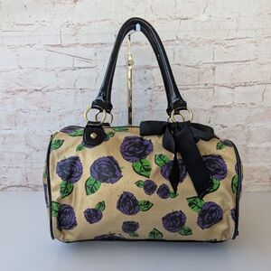 Betsey Johnson satchel handbag featuring a gold background with a purple rose an